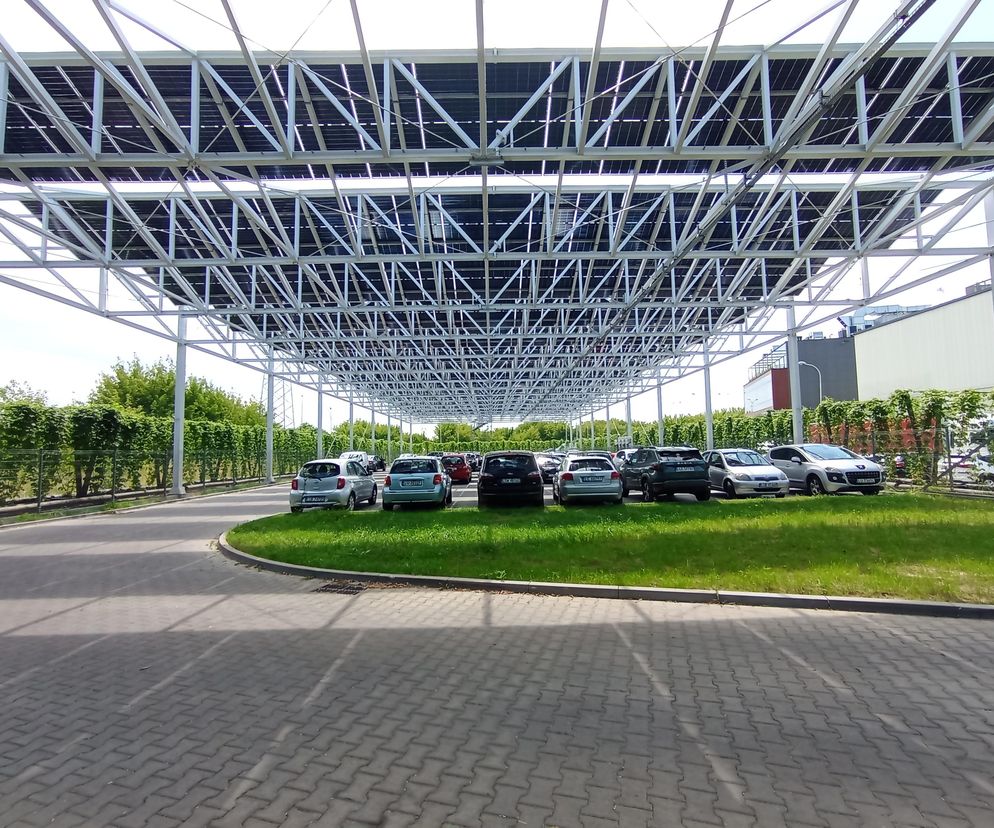 Parking z licznymi samochodami osobowymi, zadaszony nowoczesną konstrukcją wsporczą, na której umieszczono panele fotowoltaiczne. Architektura Murator Plus prezentuje to innowacyjne rozwiązanie dla browaru, zgłoszone do konkursu Życie w Architekturze 2025.