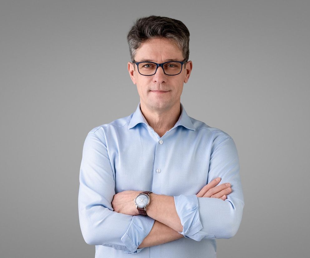Wojciech Konecki, prezes APPLiA Polska, w błękitnej koszuli z rękami skrzyżowanymi na piersi, spogląda w obiektyw na neutralnym tle. Ekspert od AGD omawia przyszłość branży, innowacje, ekologię i recykling. Więcej na ten temat przeczytasz na portalu Super Biznes.