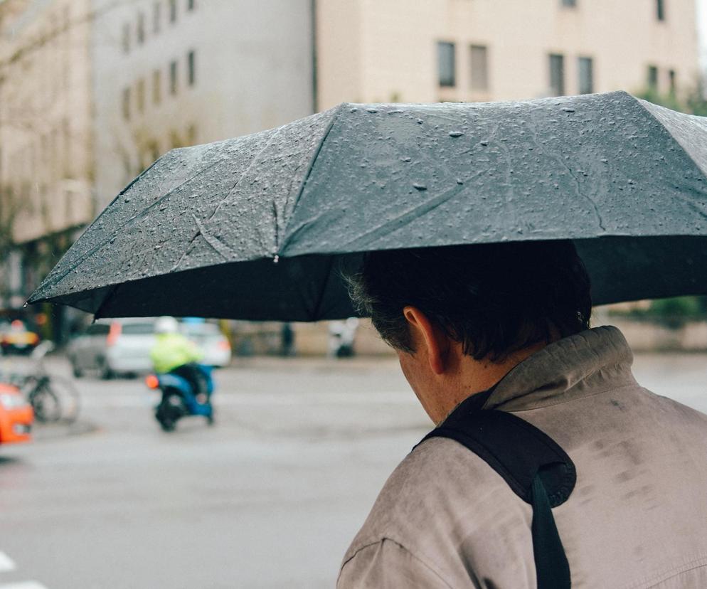 Ulewny deszcz i mężczyzna pod parasolem