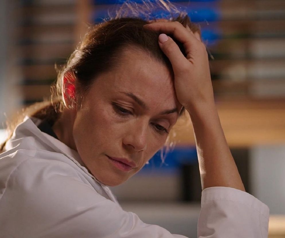 Aktorka Magdalena Turczeniewicz jako Martyna z serialu „M jak miłość”, w białym kitlu, ze smutnym, zmęczonym wyrazem twarzy, trzymająca dłoń na czole. Zdjęcie ilustruje jej trudne zachowanie i wyżywanie się na współpracownikach. Więcej o losach bohaterów na Super Seriale.