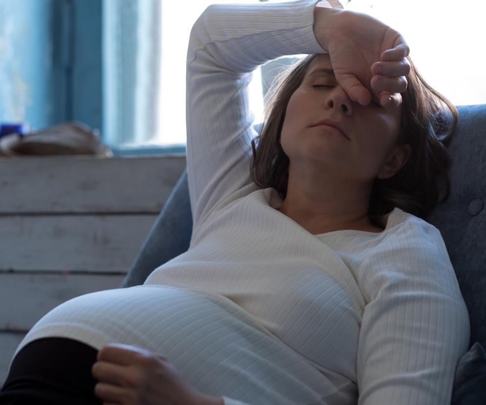 Kobieta w ciąży, trzymająca się za głową