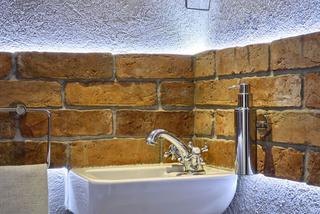 Mała łazienka w stylu folk. Ściana z cegieł i łowicki wzór - nietypowa aranżacja łazienki