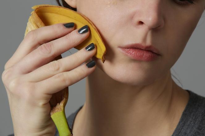 Kobieta pociera twarz skórką od banana