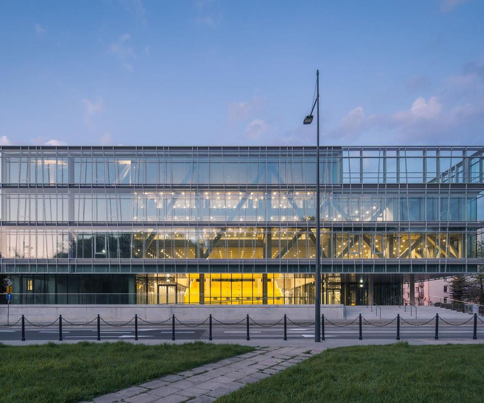 Nowoczesny budynek Wydziału Neofilologii Uniwersytetu Warszawskiego autorstwa Kuryłowicz & Associates, z przeszkloną fasadą odbijającą błękitne niebo o zmierzchu. Jasne wnętrza zapraszają otwartą architekturą, co odzwierciedla ducha konkursu Życie w Architekturze 2025. O tej realizacji przeczytasz więcej na Architektura Murator Plus.