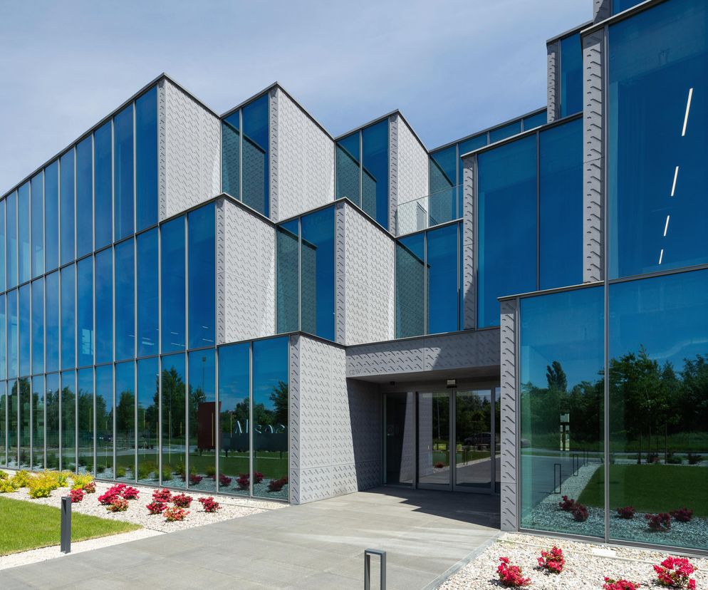 Nowoczesny biurowiec All Windows projektu Kamili Wilk i Łukasza Kościuka z elewacją z niebieskiego szkła i płyt włókno-cementowych z autorskim reliefem. Architektura Murator Plus opisuje go jako przykład funkcjonalności i świadomego projektowania.