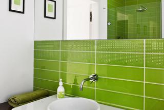 Zielona łazienka z płytkami nad umywalką