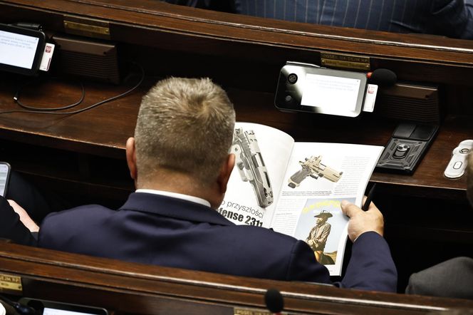 W  czasie obrad Sejmu poseł przeglądał katalog z bronią