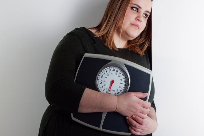otyła kobieta niosąca wagę