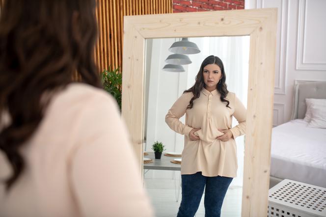 Otyła kobieta przegląda się w lustrze