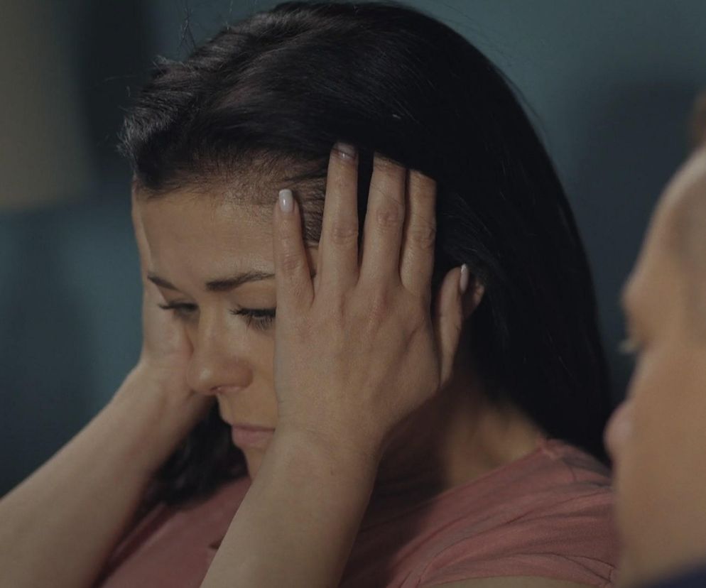 Katarzyna Cichopek jako Kinga Zduńska w serialu M jak miłość, pogrążona w stresie i koszmarach sennych, co widać na tym ujęciu jej twarzy i rąk przy głowie. Przeczytasz o tym więcej na Super Seriale.