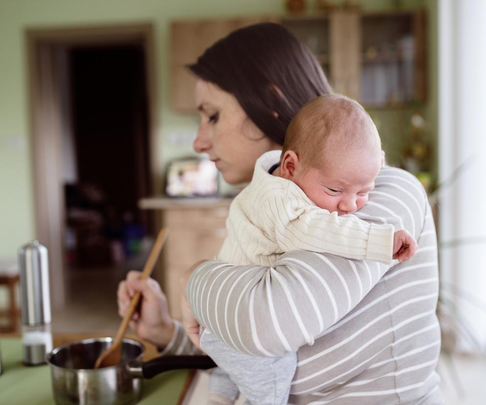 mama z noworodkiem gotująca obiad