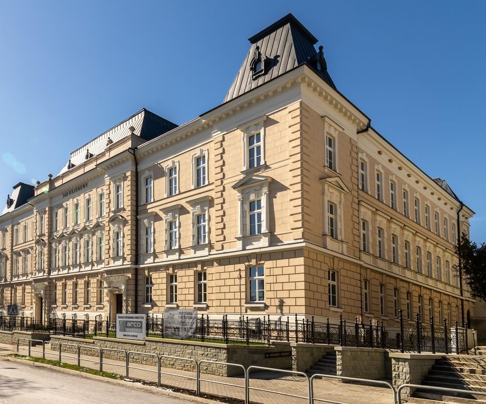 Przebudowany budynek Sądu Rejonowego w Bielsku-Białej, prezentujący jasno beżową elewację z białymi detalami i ciemnym dachem mansardowym. Projekt autorstwa mgr inż. arch. Wojciecha Łapy to przykład nagradzanej Architektury Murator Plus.