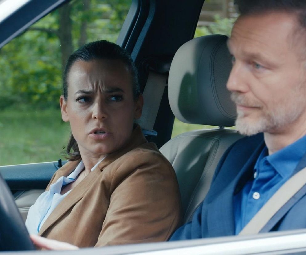 Magda (Anna Mucha) z przerażeniem patrzy przed siebie, siedząc na miejscu pasażera, obok Andrzeja (Krystian Wieczorek) z zamyśloną miną, w samochodzie po nagłym hamowaniu. Ten moment grozy Budzyńskich możesz poznać na portalu Super Seriale.