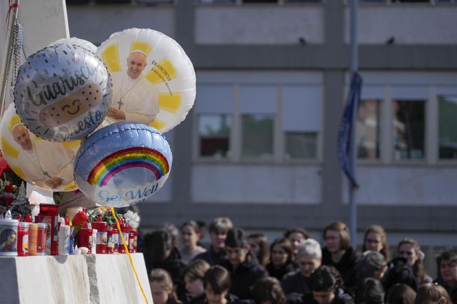 Świeczki, kartki z życzeniami, balony w kształcie serca, kwiaty składane są pod pomnikiem Jana Pawła II przed rzymską Polikliniką Gemelli