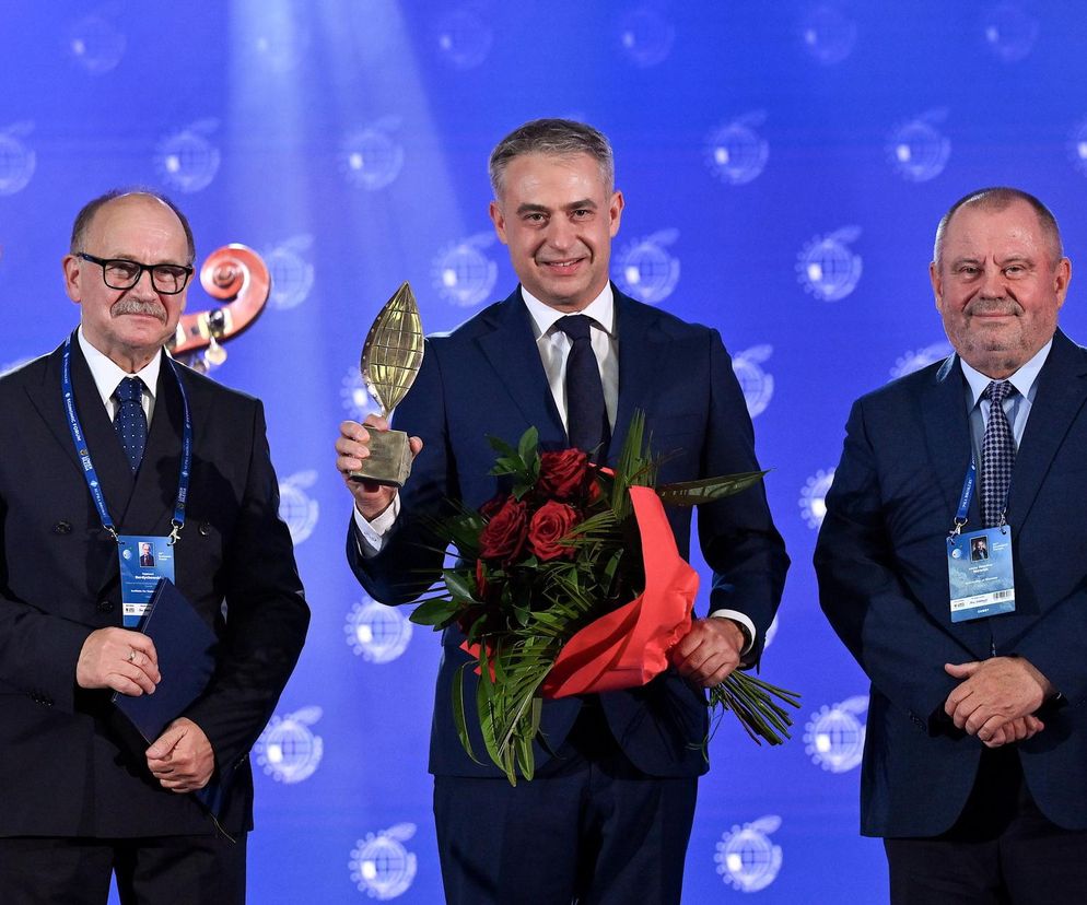 Krzysztof Gawkowski, wicepremier i minister cyfryzacji, odbiera nagrodę Człowieka Roku 2025 na Forum Ekonomicznym w Karpaczu. Zdjęcie przedstawia laureata z dwoma innymi osobami, trzymającego statuetkę i bukiet róż. Więcej informacji o tym wydarzeniu i osiągnięciach ministra znajdziesz na portalu Super Biznes.