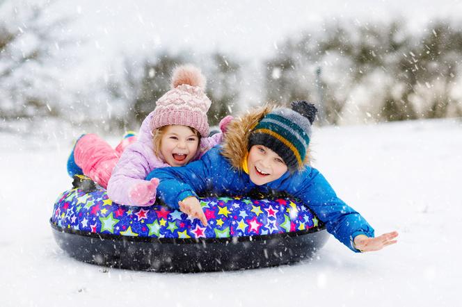 dzieci zjeżdżające z górki po śniegu