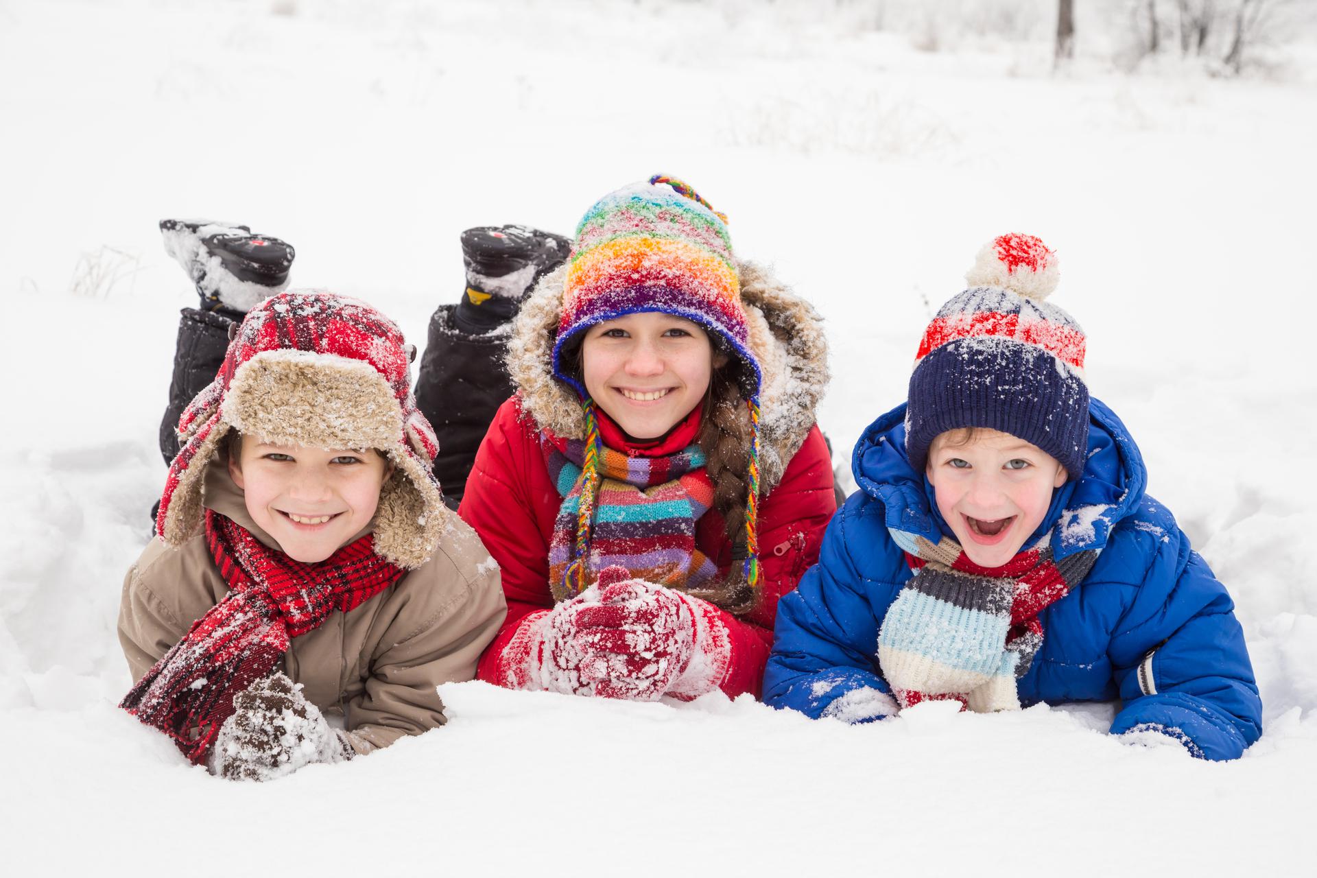 Когда начинаются зимние. Дети лежат зимой на снегу ромашкой. Snow Kids команда. Дети лежат на снегу и рот. Картинка для детей, где дети лежат на снегу.