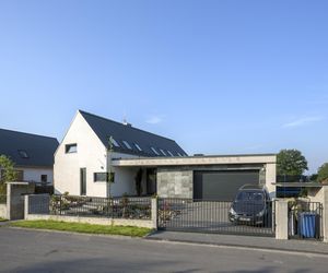 Dwie bryły. Od frontu na mieszkalną wygląda jedynie część bryły pod dwuspadowym dachem – nawiązująca do tradycyjnego kształtu domu. Już wkrótce sąsiadujący z nią płaski dach – taras porośnie trawa, która ożywi oszczędną, minimalistyczną architekturę
