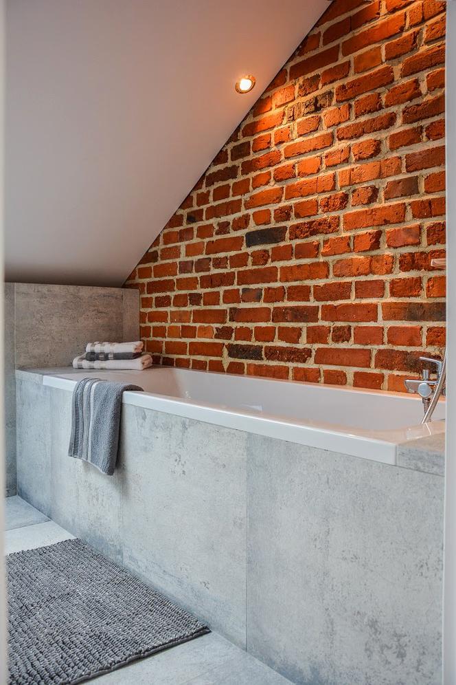 Łazienka na poddaszu z cegłą na ścianie