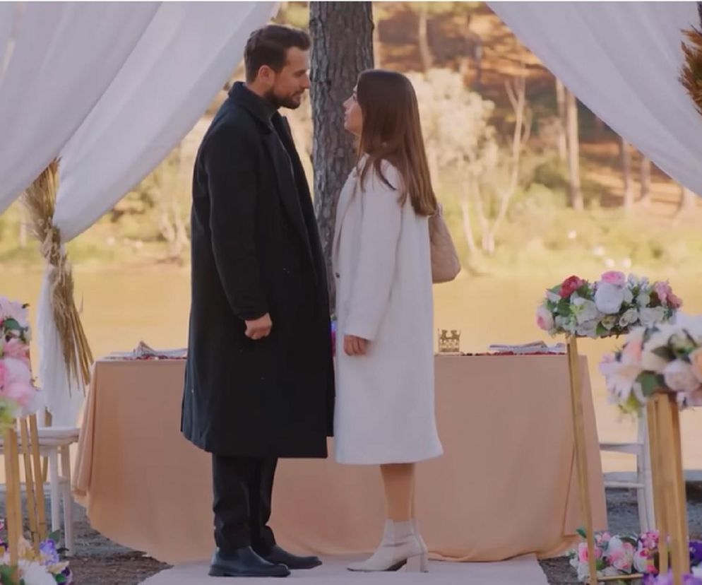 Para, Kuzey i Sila, stoi naprzeciwko siebie w romantycznej scenerii oświadczyn nad jeziorem. Altana z białymi zasłonami i bukietami kwiatów tworzy tło dla wzruszającej chwili. Szczegóły serialu Miłość i nadzieja znajdziesz na Super Seriale.