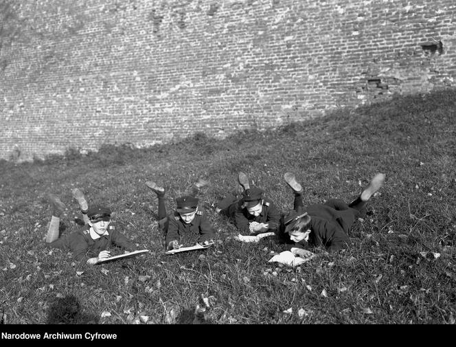 Chłopcy przeglądający książki na trawie przed murami Wawelu (1928 r.)