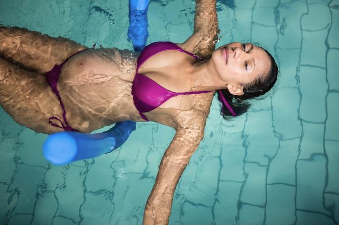 Kobieta w ciąży leżąca na wodzie w basenie