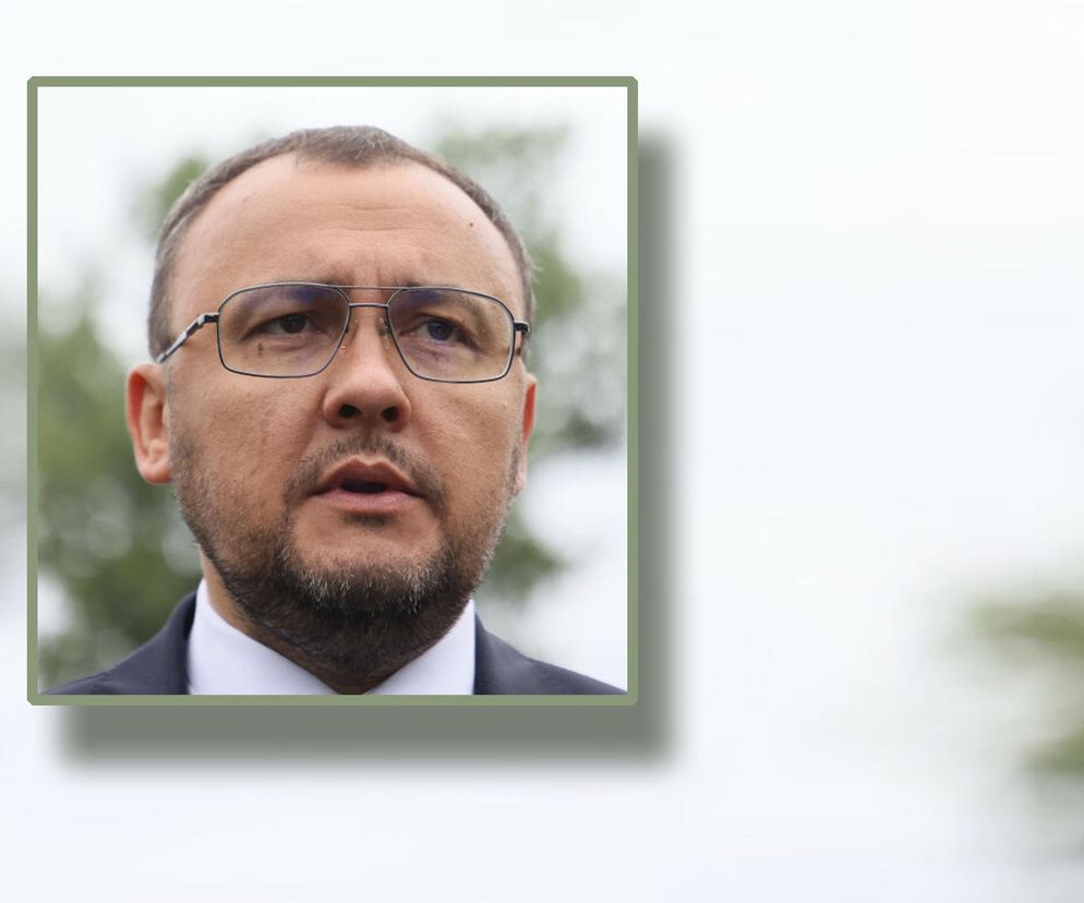 Portret Wasyla Bodnara, ambasadora Ukrainy w Polsce, z bliska. Mężczyzna z ciemnym zarostem i okularami spogląda przed siebie. Ubrany jest w elegancki garnitur z białą koszulą. Tło jest rozmyte, z widocznymi odcieniami zieleni, sugerującymi plener. O relacjach polsko-ukraińskich można przeczytać na Super Biznes.