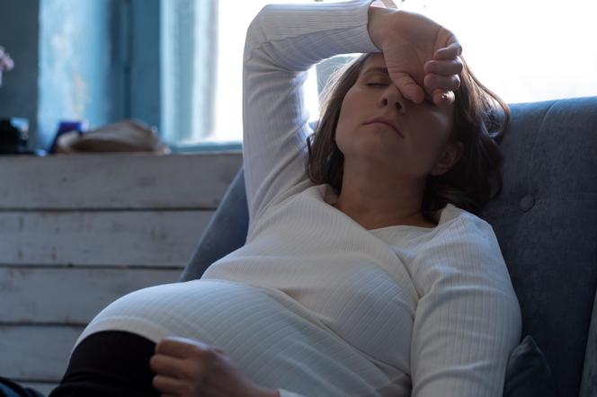 Kobieta w ciąży, trzymająca się za głową