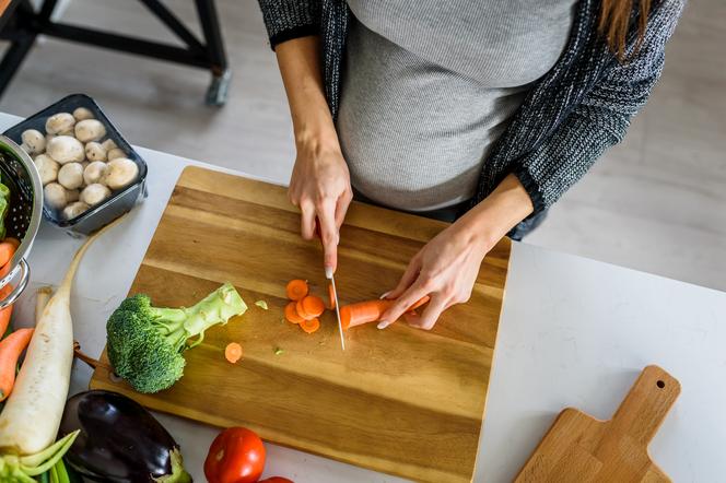 kobieta w ciąży krojąca warzywa