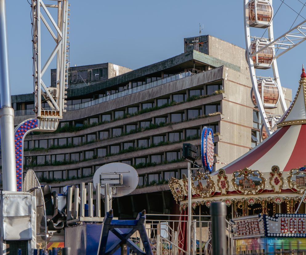 Zniszczony Hotel Forum w Krakowie, będący ikoną brutalizmu, z zaniedbanymi tarasami i elewacją, otoczony elementami wesołego miasteczka, takimi jak karuzela i diabelski młyn. O jego przyszłości można przeczytać na Architektura Murator Plus.