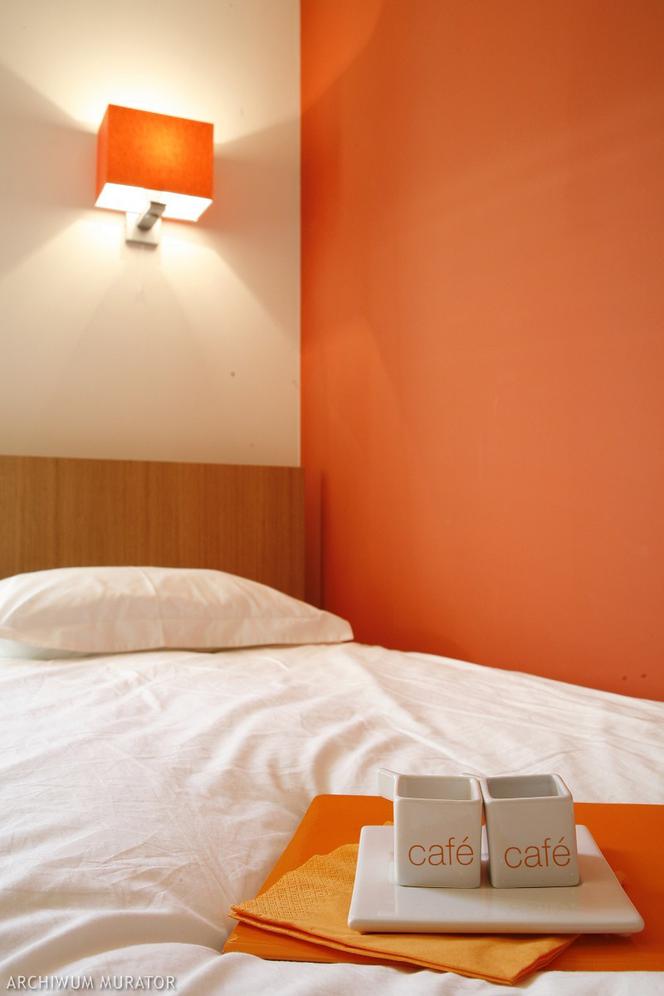 Jasna sypialnia z pomarańczowymi dodatkami
