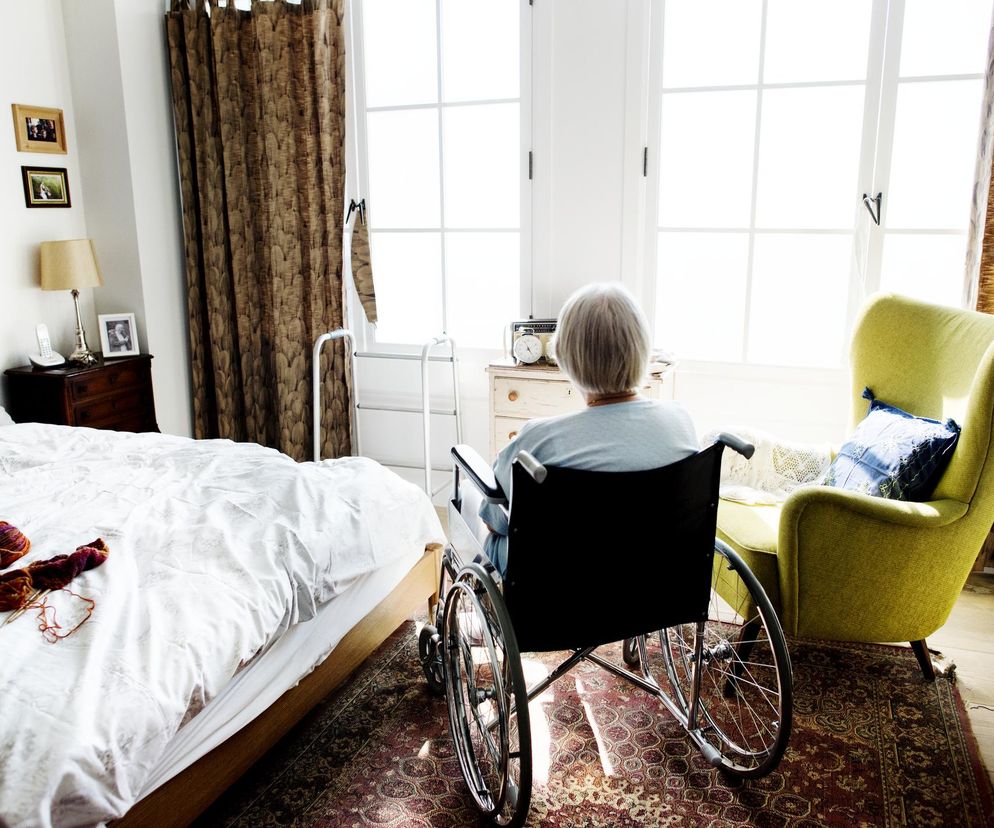 Starsza osoba na wózku inwalidzkim w pokoju w ZOL-u
