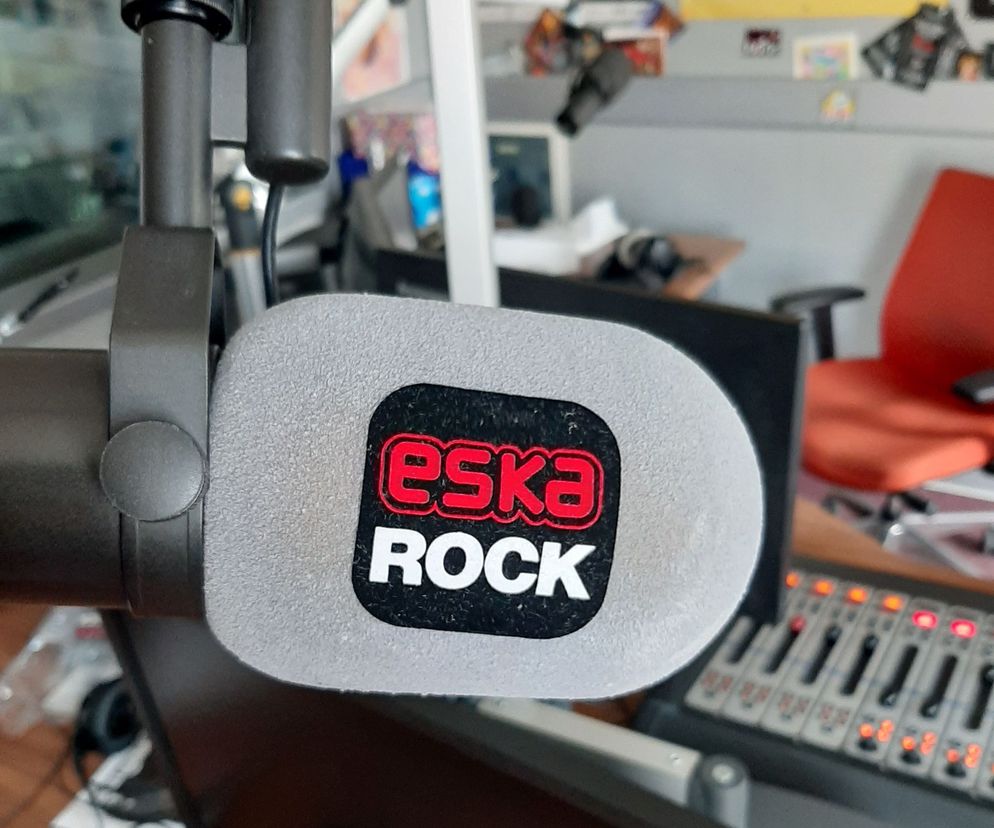 Mikrofon radiowy z gąbką z logo ESKA ROCK, blisko studyjnego stołu mikserskiego z podświetlonymi suwakami, w tle rozmyte elementy studia. Artykuł na Poradnik Zdrowie dotyczy programu Drogowskazy w ESKA ROCK, o radzeniu sobie w domowej izolacji.