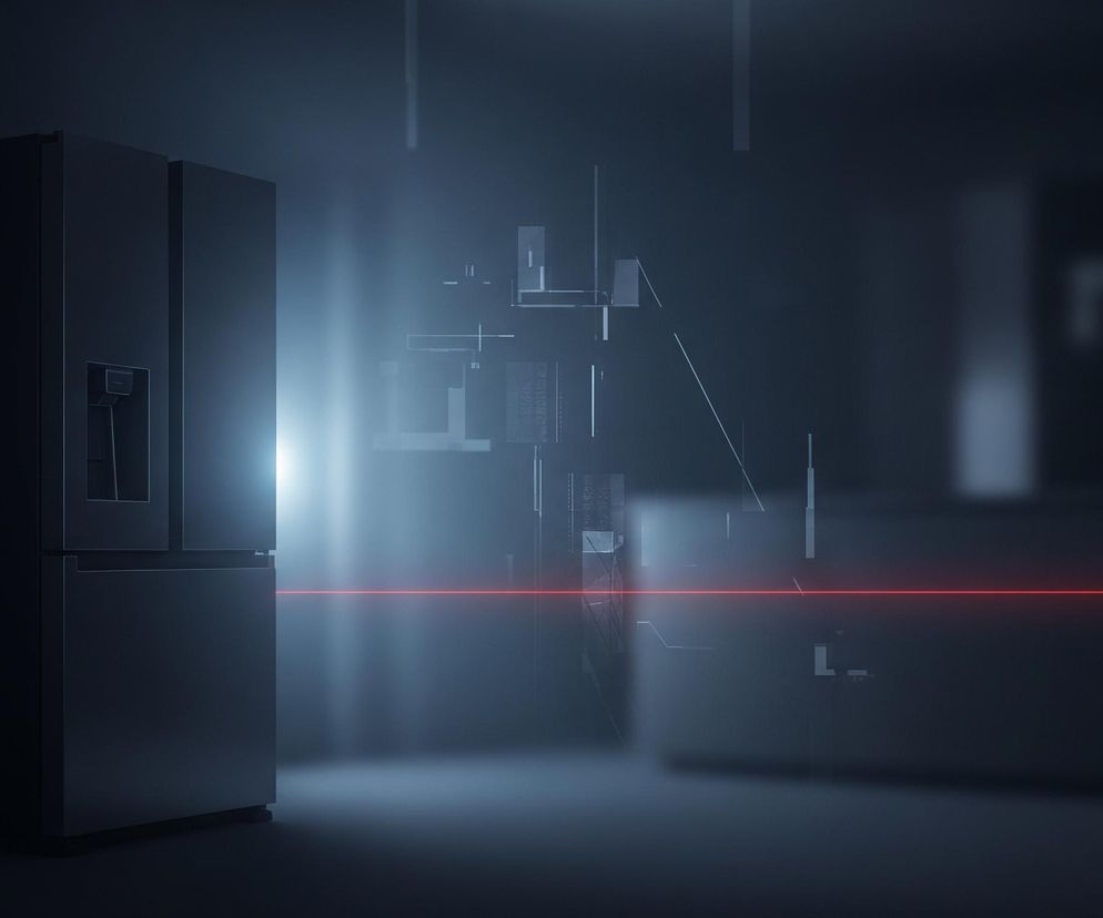 W lewej części kadru znajduje się ciemnoszara lodówka z czterema drzwiami i dystrybutorem wody na górnych lewych drzwiach. Pozioma, jasnoczerwona linia lasera przecina kadr od lewej do prawej, zaczynając od prawego boku lodówki. Od środka kadru w prawo unosi się delikatna, niebieskawa mgiełka świetlna, w której zanurzone są abstrakcyjne, geometryczne kształty złożone z linii i prostokątów. Całe tło jest ciemne, stopniowo rozjaśniające się ku środkowi i w górnej części, tworząc minimalistyczną i futurystyczną kompozycję.
