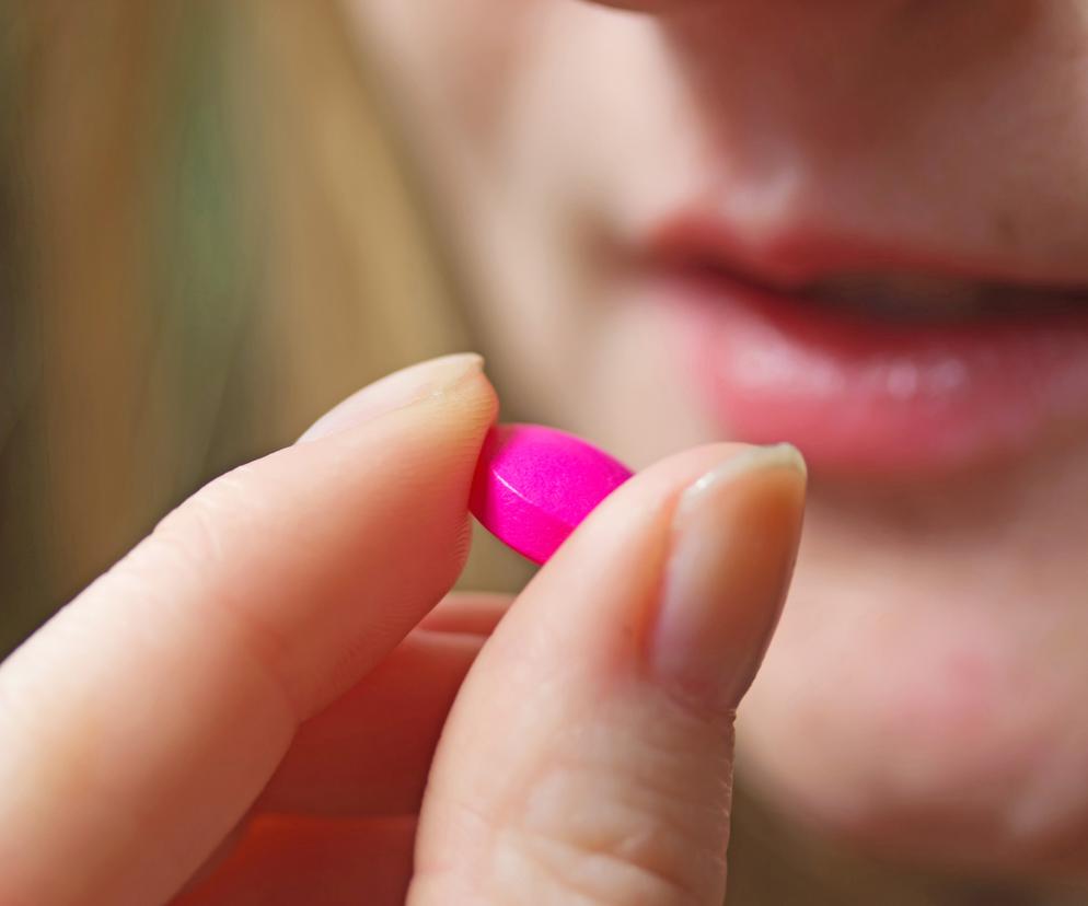 Kobieta przyjmuje różową pigułkę