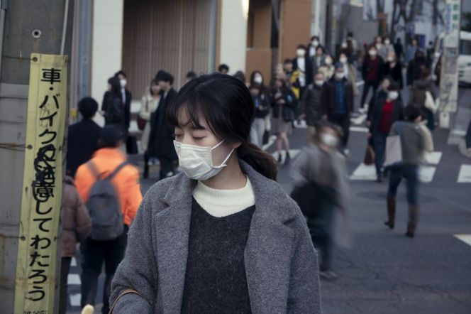 Japonia: kobieta w maseczce ochronnej przechodzi przez ulicę