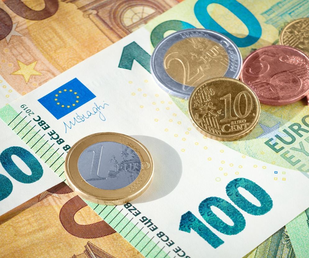 Banknoty euro o nominałach 50 i 100, oraz monety euro, w tym 1 i 2 euro, a także centy. Obraz symbolizuje aktualne kursy walut i stabilność złotego, o czym przeczytasz więcej na Super Biznes.