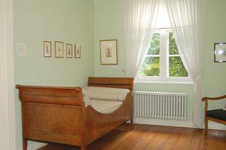 Skromna sypialnia w stylu biedermeier – łóżko o typowej dla okresu formie bateau, z uwypuklonym rysunkiem słojów drewna. 