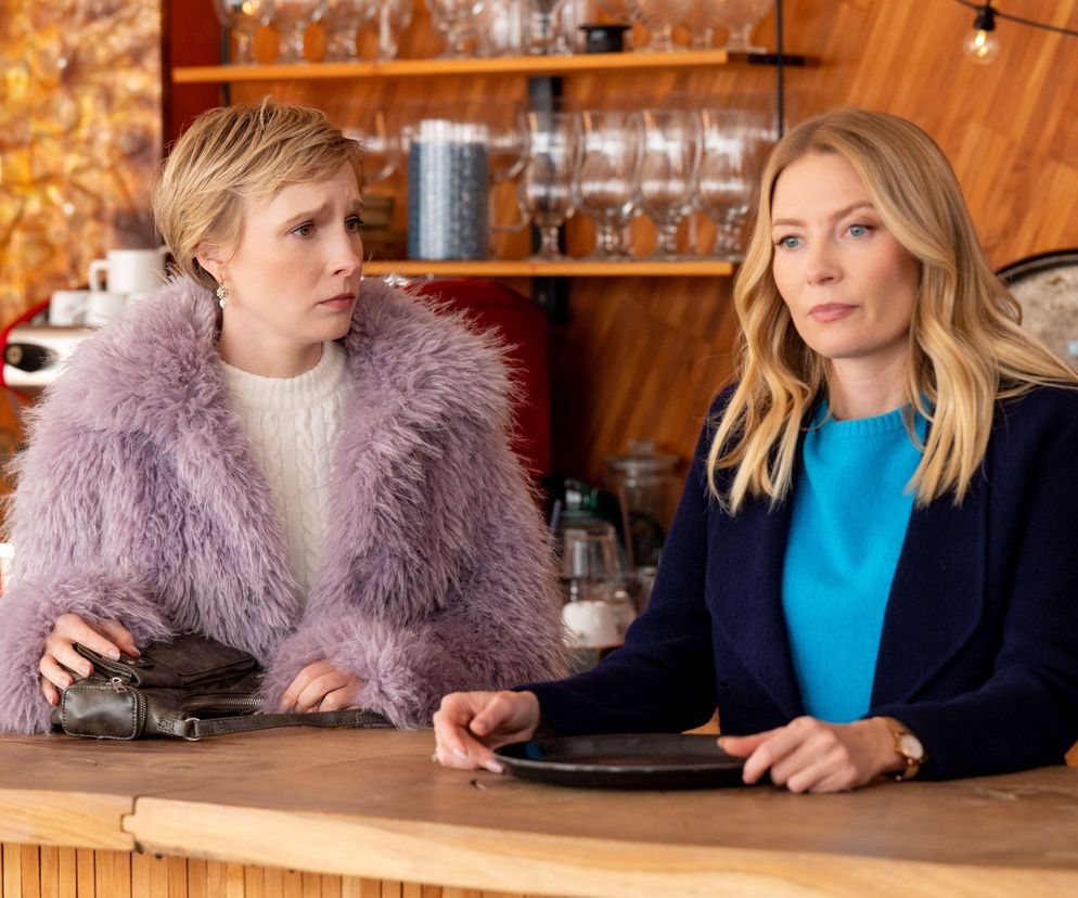 Weronika Nockowska jako Sonia i Karolina Chapko jako Dominika w scenie z serialu Barwy szczęścia. Kobiety stoją przy drewnianym barze, a w tle widać półki z naczyniami i lampki. Sonia, w fioletowym futerku, wydaje się zmartwiona, Dominika w granatowym płaszczu i błękitnym swetrze ma poważny wyraz twarzy. Więcej o ich losach na Super Seriale.