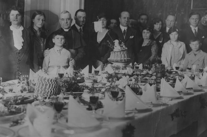 Uczestnicy spotkania Wielkanocnego przy zastawionym świątecznymi potrawami stole (1931)