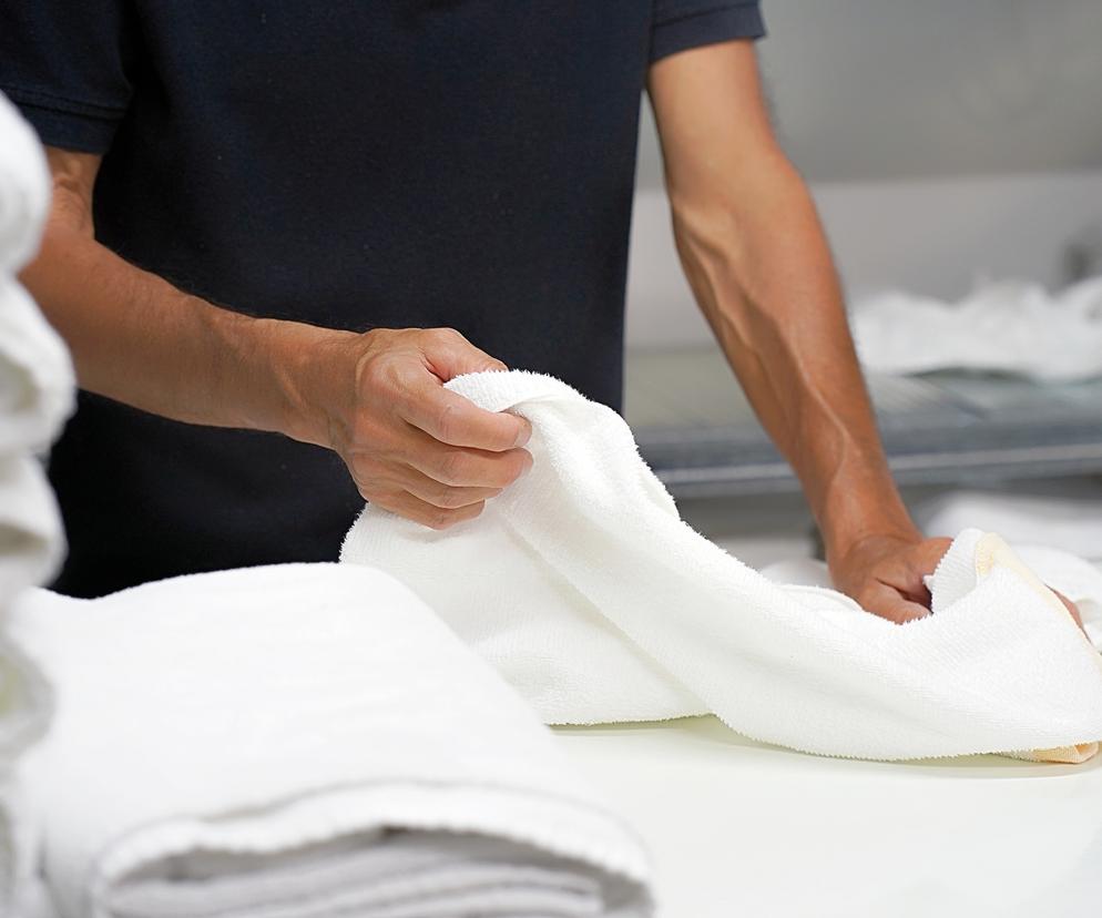 Mężczyzna składa ręcznik w pralni hotelowej 