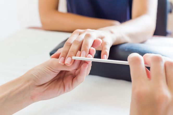 Stylistka paznokci wykonująca manicure