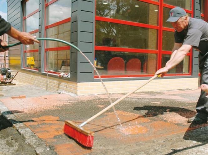 Zaszlamowanie szczelin piaskiem za pomocą węża z wodą i szczotki