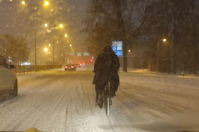Białystok. Śnieg sparaliżował ulice, a rowerzysta próbuje jechać środkiem drogi 