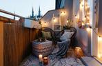 Mały balkon w bloku lub kamienicy z czarnym rattanem.