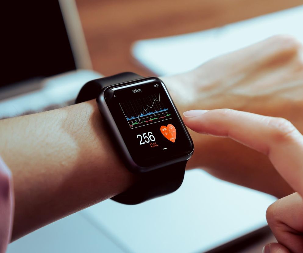 Smartwatch na nadgarstku, którego ekran dotykowy pokazuje aplikację do monitorowania aktywności, tętna i spalonych kalorii. Kobieta dotyka palcem wyświetlacza. Taka oferta bonusowa, jak smartwatch Apple Watch SE 3, za otwarcie konta, czeka na Ciebie w Super Biznes.