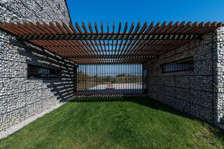 Gabiony, wszędzie gabiony. Tu cała bryła domu wykończona jest koszami gabionowymi. Jest i ogromne okno