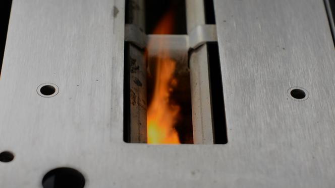Płomień palący się pod powierzchnia rusztu w palenisku manualnym
