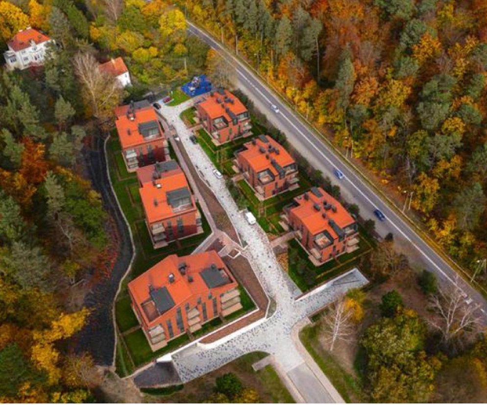 Osiedle Oliva Koncept w Gdańsku, autorstwa Arch-Deco, architekci Zbigniew Reszka i Michał Baryżewski. Widok z lotu ptaka na kompleks sześciu nowoczesnych budynków z pomarańczowymi dachami, wkomponowanych w jesienny krajobraz wzgórz. Więcej o architekturze na Architektura Murator Plus.