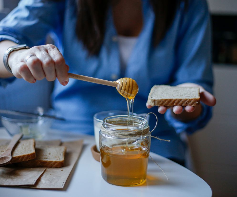 Kobieta smaruje kanapkę miodem